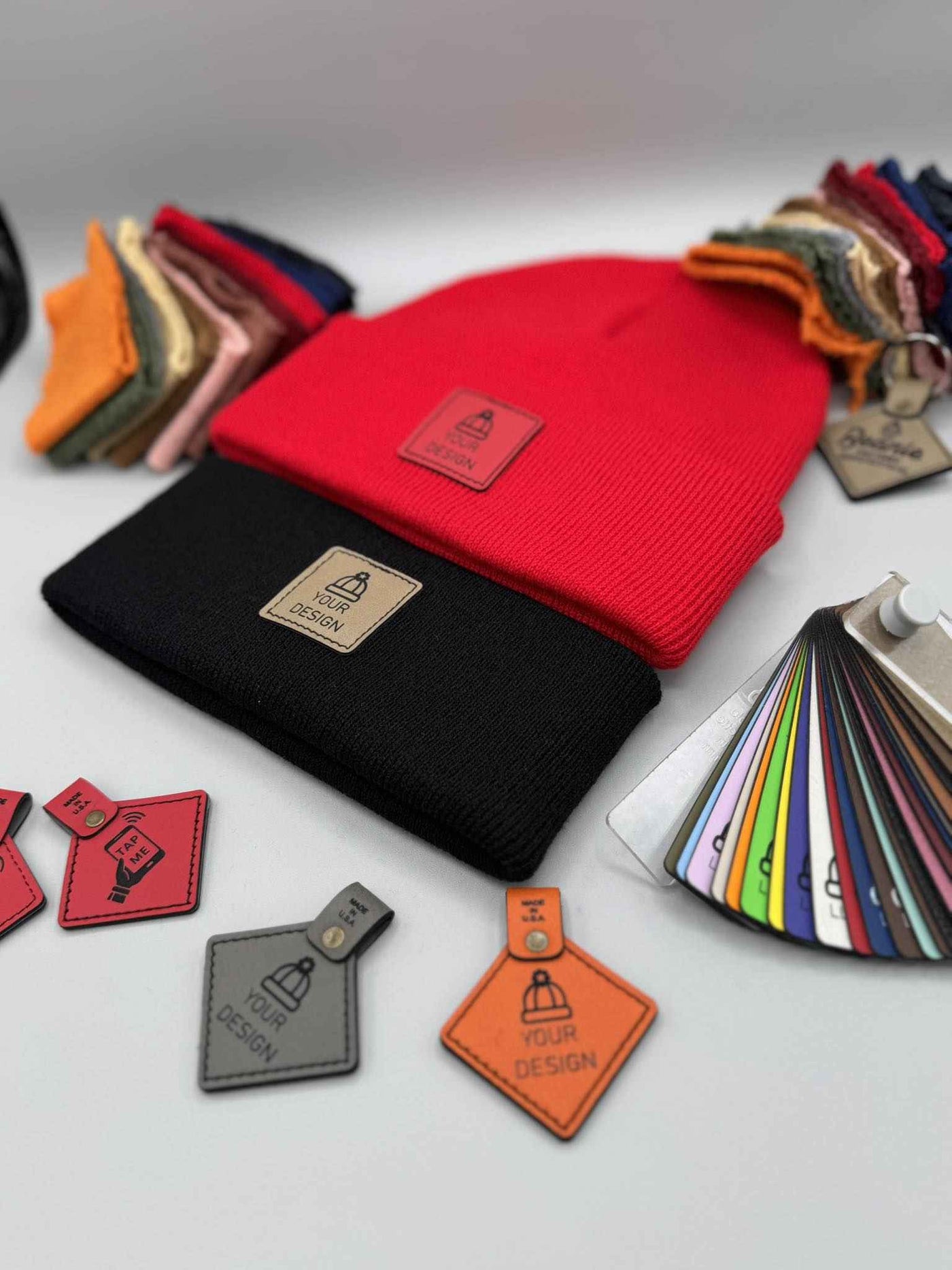Collection of colorful leather tags and a red beanie on a gray background
