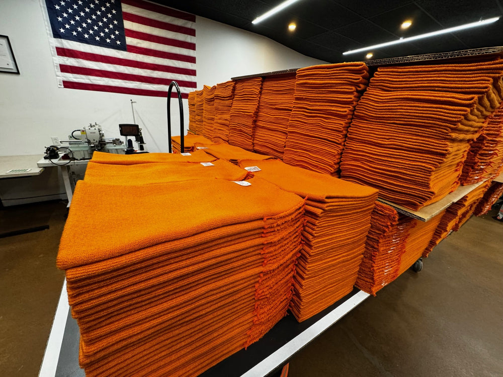 Stacks of orange fabric beanies on a table with an American flag in the background