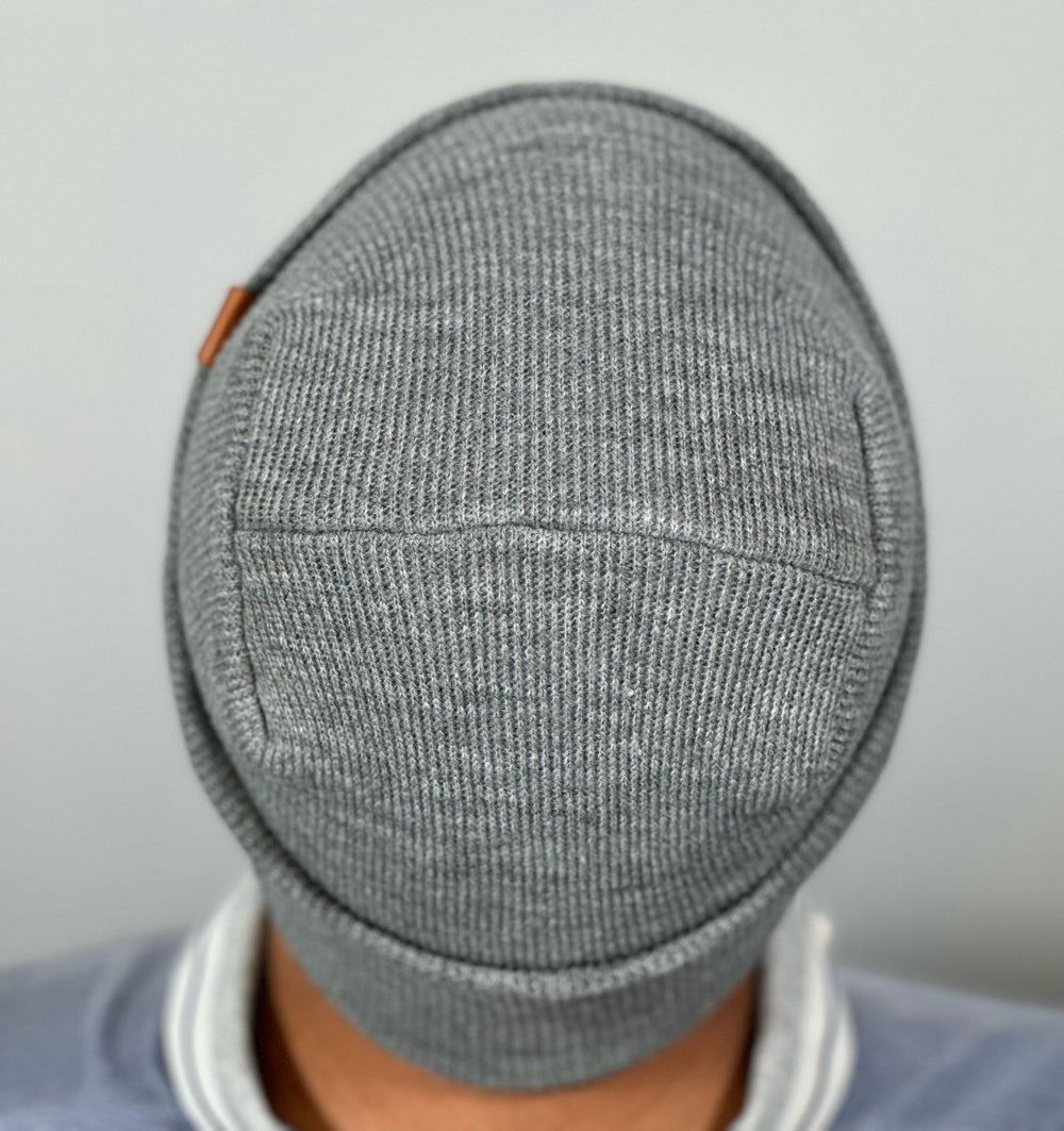 A gray hat featuring The Beanie Factory's lay-flat, irritation-free H-Stitch is modeled for the camera.