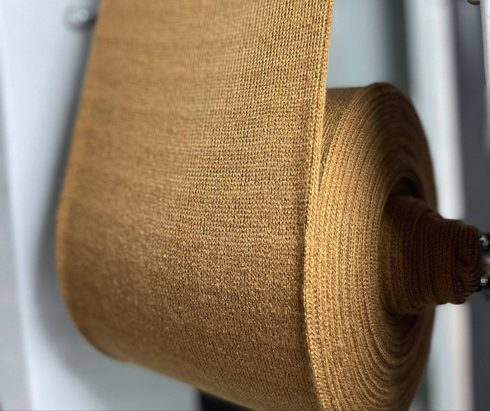 Roll of brown fabric on a machine with a white background